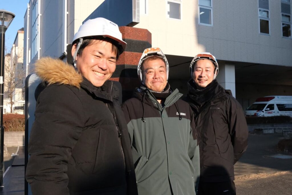 KDDIスマートドローン 貴島氏（左）とプロジェクトメンバーら（筑波メディカルセンター前で撮影）